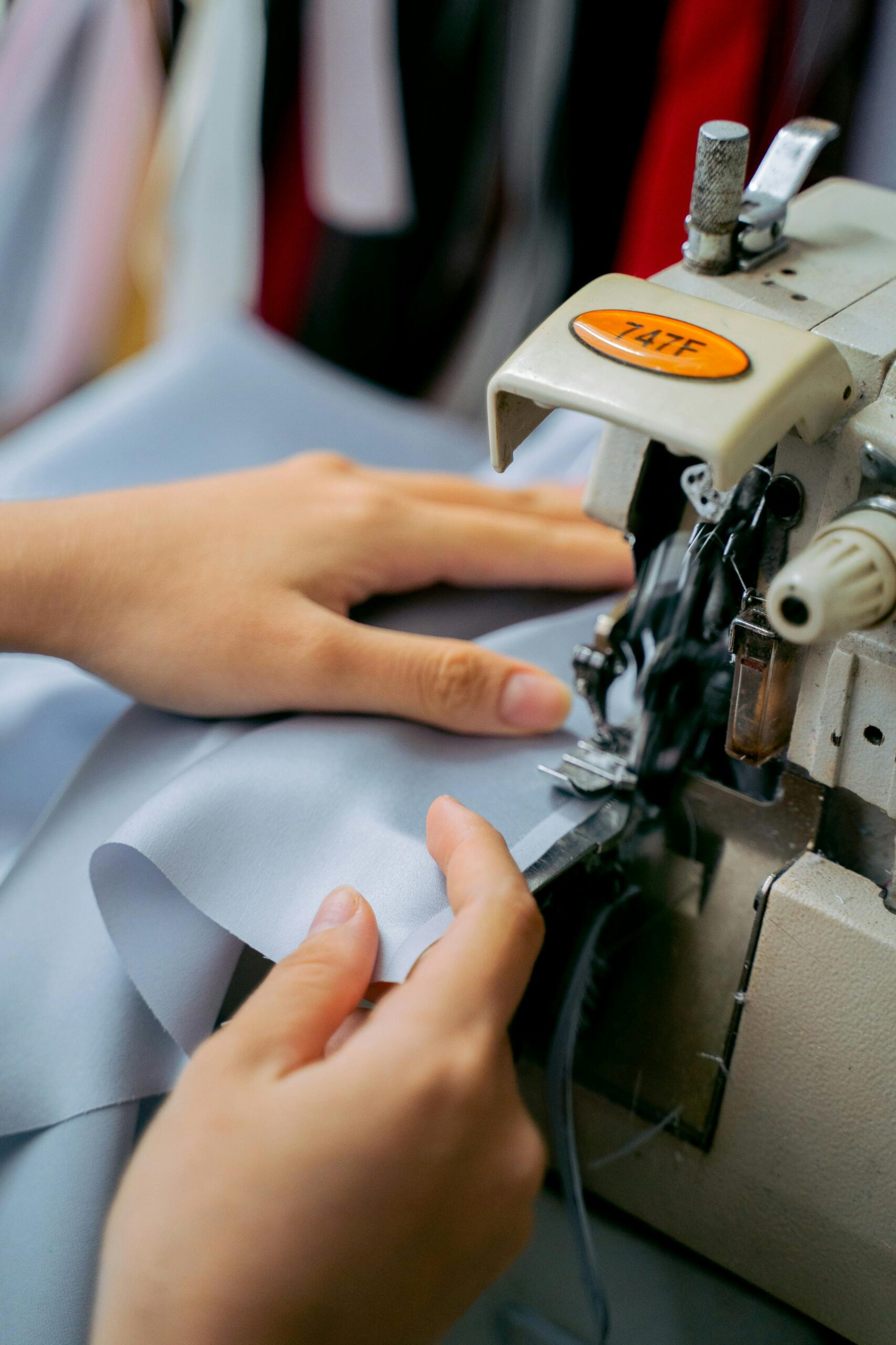 Close-up of hands sewing fabric with a sewing machine, showcasing handmade craftsmanship.
